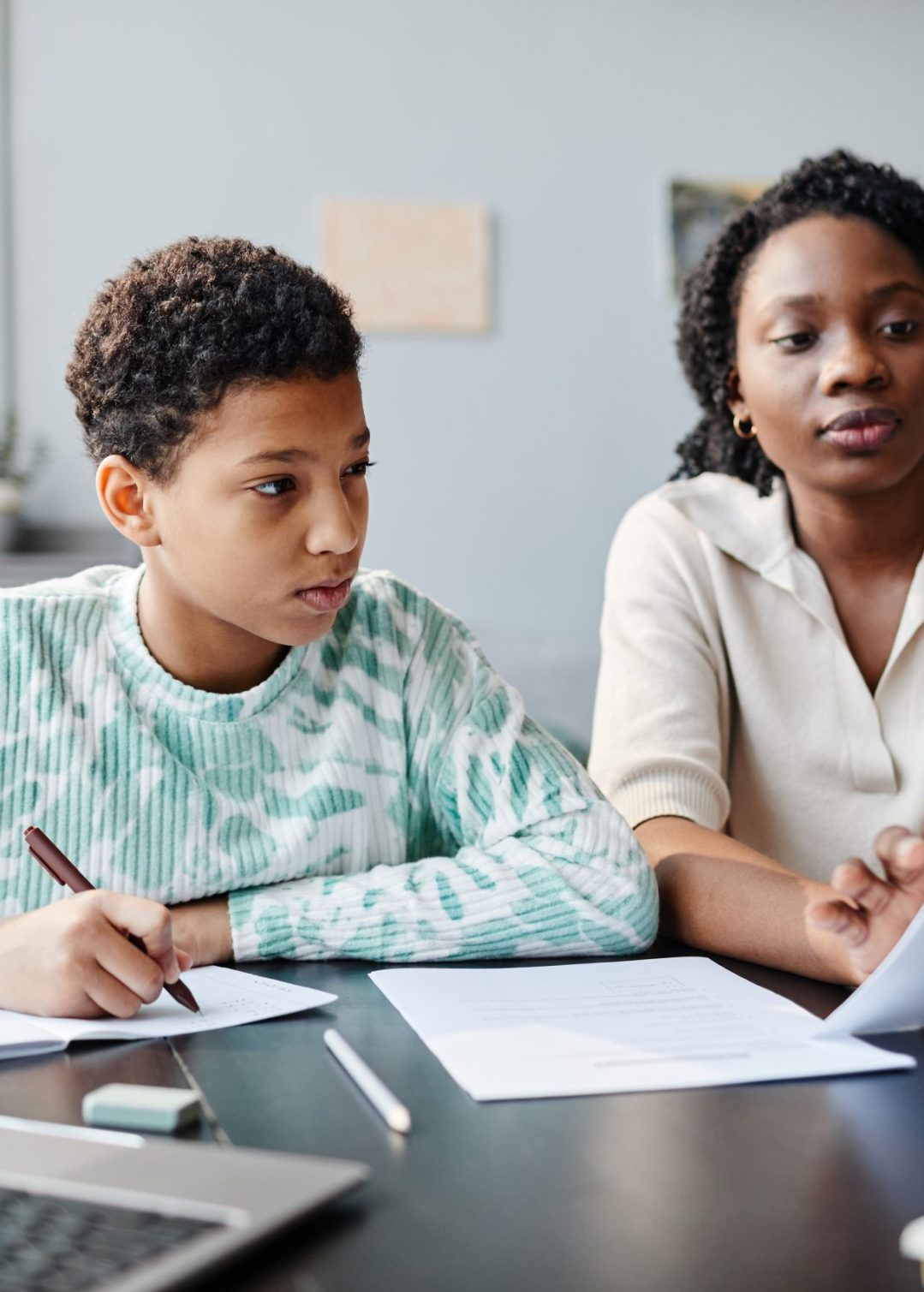 Young African American Girl Studying with Tutor Portrait of black teenage girl studying at home with mother or tutor helping preparing for exam